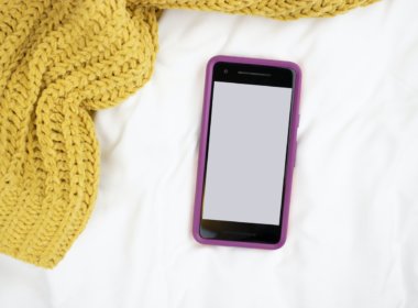 phone and yellow blanket on bed